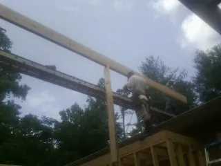 Carpenter setting a ridge beam over a new addition frame — Ice Dam Removal by Roofing Brothers in Oquawka