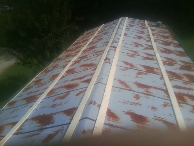 Rusted metal roof panels with new wood purlins before replacement — Storm Damage Roof Repair in Oquawka by Roofing Brothers