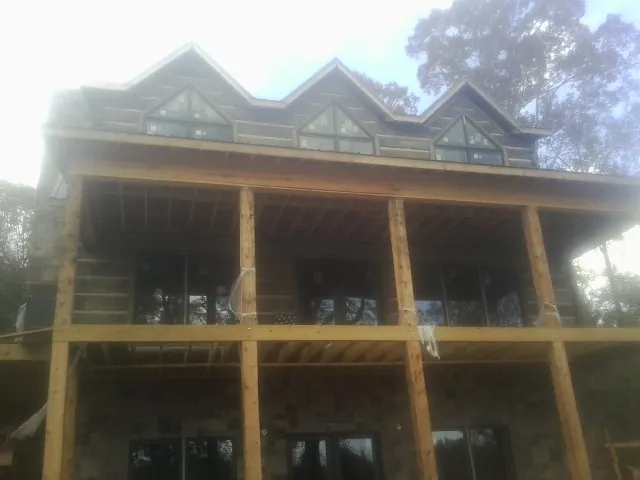Dormers and porch framing on a large log home under construction in Oquawka