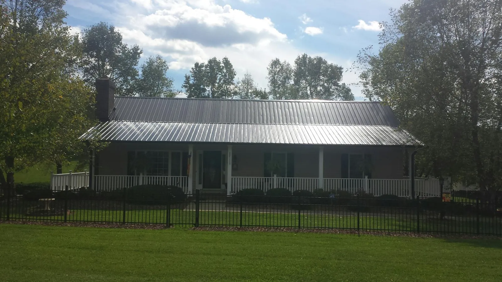 Gray metal roof on a brick ranch with a full width front porch — Gutter Guard Installation work by our crew in Oquawka