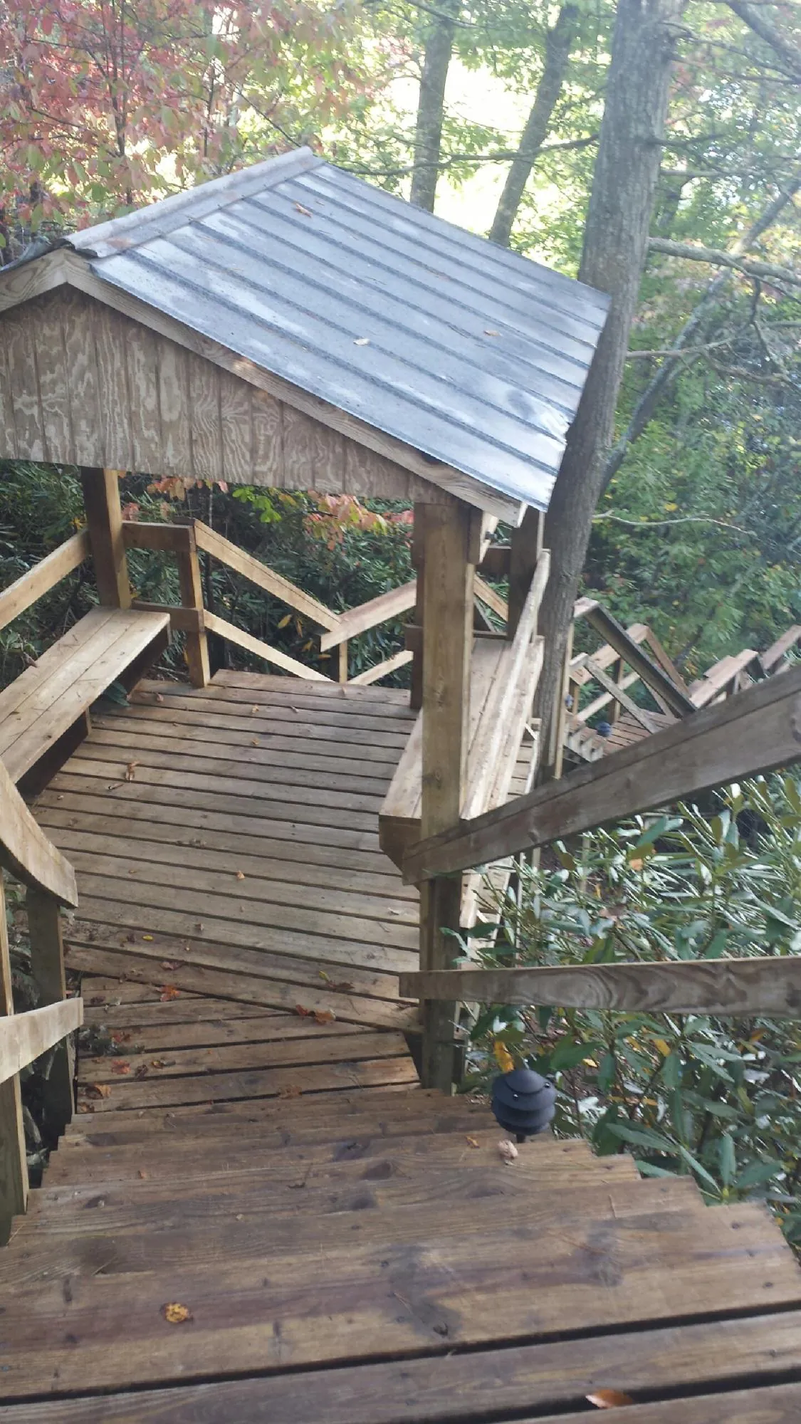 Metal roofed shelter over wooden steps on a wooded walkway — Skylight Repair & Installation work by our crew in Oquawka